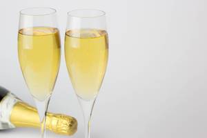 Two Full Glasses of Champagne with Bottle behind it on white Background