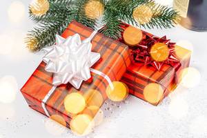 Two gift boxes with ribbons and bows on a background of snow and Golden bokeh