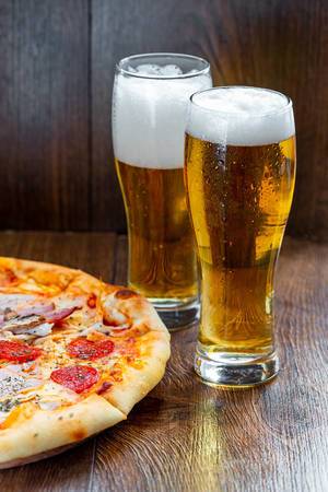 Two glasses of cold beer with pizza