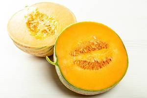 Two halves of ripe orange melon with seeds inside
