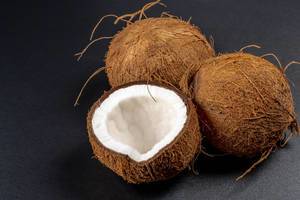 Two whole and half coconuts on a black background (Flip 2020)