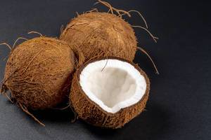 Two whole and half coconuts on a black background