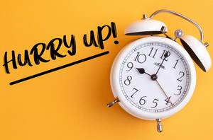 Überwinden Prokrastination: Wecker mit dem Text ‘Hurry up!’ vor gelbem Hintergrund