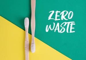 Umweltfreundliche Holzzahnbürste auf grünem und gelben Untergrund und dem Text "Zero Waste"