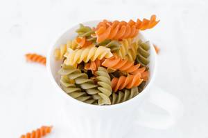 Uncooked three-colored pasta with spinach and tomato