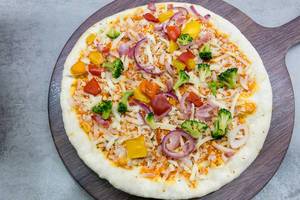Ungebackene vegetarische Pizza auf einem Holzschneidebrett