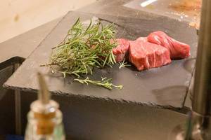 Ungebratenes, saftige Steaks mit Bund Rosmarin auf Schieferplatte