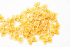 Ungekochte Farfalle, Pasta in Schmetterlingsform, verteilt auf weißem Untergrund