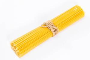 Ungekochte Spaghetti mit Bastschnur gebunden vor weißem Hintergrund