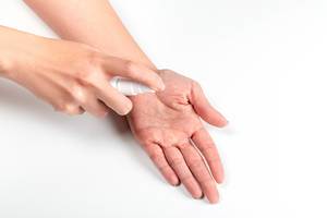 Using an antiseptic spray to disinfect hands on a white background