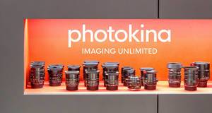 Various Leica lenses in front of an orange background, exhibited for the photo fair with the image title photokina imaging unlimited