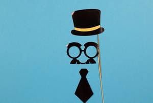 Vatertagsknozept - Papierhut, Brille mit Schnurrbart und Krawatte auf blauem Hintergrund