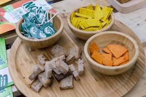 Vegane Käseproben in Schälchen aus Holz mit Brot auf einem Brettchen