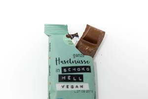 Vegane Schokoladentafel in der aufgerissenen Verpackung von HaselHerz mit Kokosmus, Kakao und Haselnüssen aus biologischem Anbau