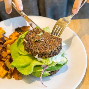 Veganer, glutenfreier Inside Out Quinoa Burger wird mit Messer und Gabel beim True Food Kitchen Restaurant in Chicago gegessen