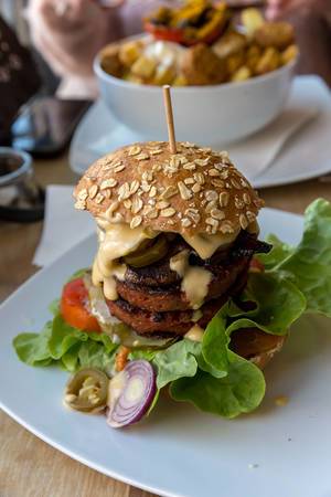 Veganes Burger mit Beyond Meat Patty, Ketchup Special, Salat, Gewürzgurken, Tomaten und Portobello-Pilz Bacon