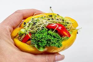 Veganes Sandwich aus Gemüse und Keimen in weiblicher Hand