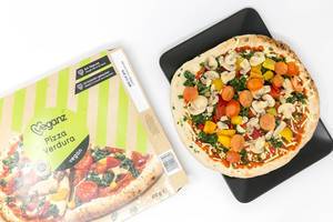 Veganz Pizza Verdura - Tiefkühlpizza mit Pilzen, Spinat, Paprika und Tomaten mit Verpackung in der Aufsicht auf einem schwarzen Teller und weißem Hintergrund