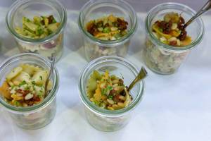 Vegetarian pasta salad with broccoli, mushrooms, dried tomatoes and pine nuts in small jars at the BarCamp in Bonn