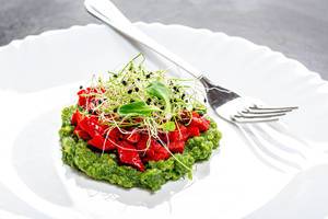 Vegetarian salad layers with fresh vegetables and onion seed sprouts on a white plate with fork