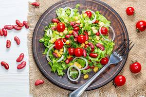 Vegetarischer Salat mit Gemüse und roten Bohnen auf einem braunen Teller, auf einem Leinentuch