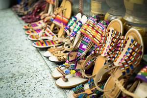 Verkaufsauslage von typischen, handgemachten Sandalen aus Leder und bunten Riemen in den Straßen von Guatemala