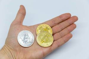 Verschiedene Bitcoin-Münzen in der Hand