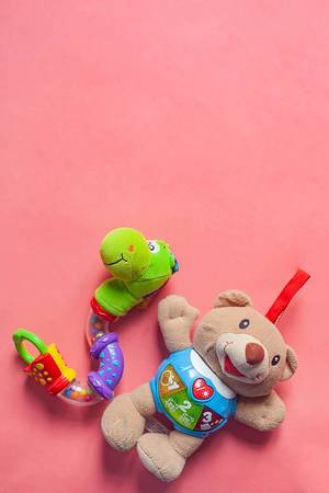 Vertical photo of child rattles with copy space on the top. Bear and snake toys for newborn kids on the pink background. Copy space.