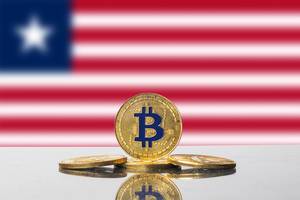 Vier goldene Bitcoins angeordnet vor der Flagge von Liberia