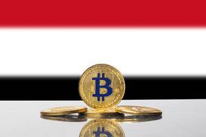 Vier goldene Bitcoins vor der dreifarbigen Flagge des Yemen