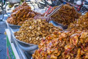 Vietnamesischer Straßenhändler verkauft frittierte Meeresfrüchte auf Marktwagen in Vung Tau