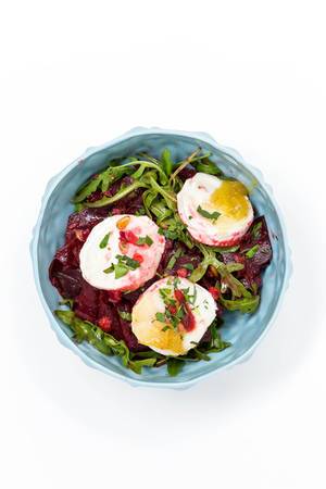 View from above of salad of beetroot, rocket and poached eggs in front of white background