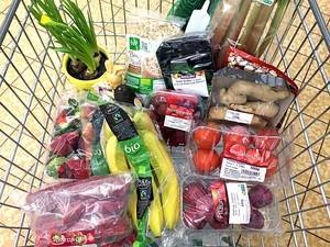 View from above of shopping cart with fruit and vegetables packaged in plastic