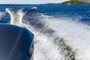 View from the stern of a yamarin powerboat overlooking the engine and waves on blue water of Lake Päijänne in Finland