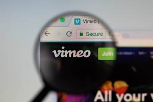 Vimeo-Logo am PC-Monitor, durch eine Lupe fotografiert
