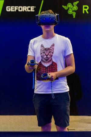 Visitor with cat shirt gaming with VR headset and controllers