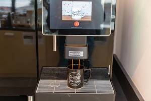 Vollautomat-Kaffeemaschine Franke A800 gießt das Heißgetränk in eine "Do what you love - WeWork" - Tasse