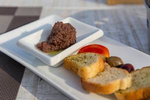 Vorspeise auf griechische Art: schwarze Oliven, Cherrytomaten und fein gehackte Oliven in Olivenöl