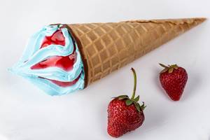 Waffle cone with blue ice cream and strawberries