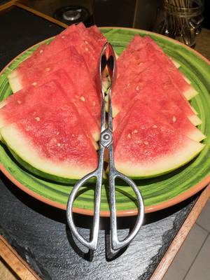 Wassermelonenscheiben auf einem Teller mit einer Zange zum bedienen