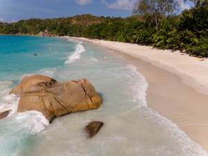 Waves of the blue Indian Ocean break at a granite rock next to Anse Lazio Beach in Praslin, Seychelles