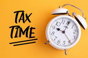 Wecker mit dem Text ‘Tax time’ vor gelbem Hintergrund