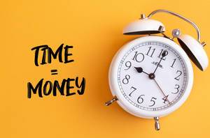 Wecker mit dem Text ‘Time = Money’ vor gelbem Hintergrund