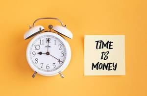 Wecker und ein Zettel mit ‘Time is money’ Text vor gelbem Hintergrund