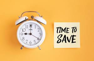 Wecker und ein Zettel mit ‘Time to save’ Text vor gelbem Hintergrund
