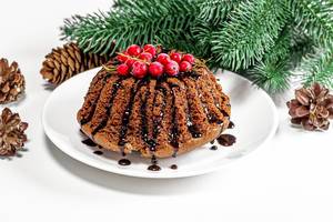 Weihnachtlicher Schoko-Kuchen mit roten Johannisbeeren und Topping auf einem Teller mit Weihnachtsdeko