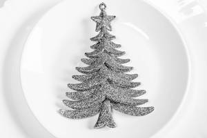 Weihnachtsdekor: silberner, glitzernder Tannenbaum auf einem gedeckten Tisch