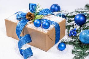 Weihnachtsgeschenk in Naturpapier mit blauem Band, von Schnee bedeckt
