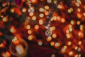 Weihnachtskristall an einem Tannenzweig mit Lichtern im Hintergrund