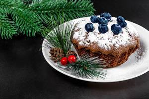 Weihnachtskuchen: Schoko-Cupcake mit Heidelbeeren vor schwarzem Weihnachtshintergrund